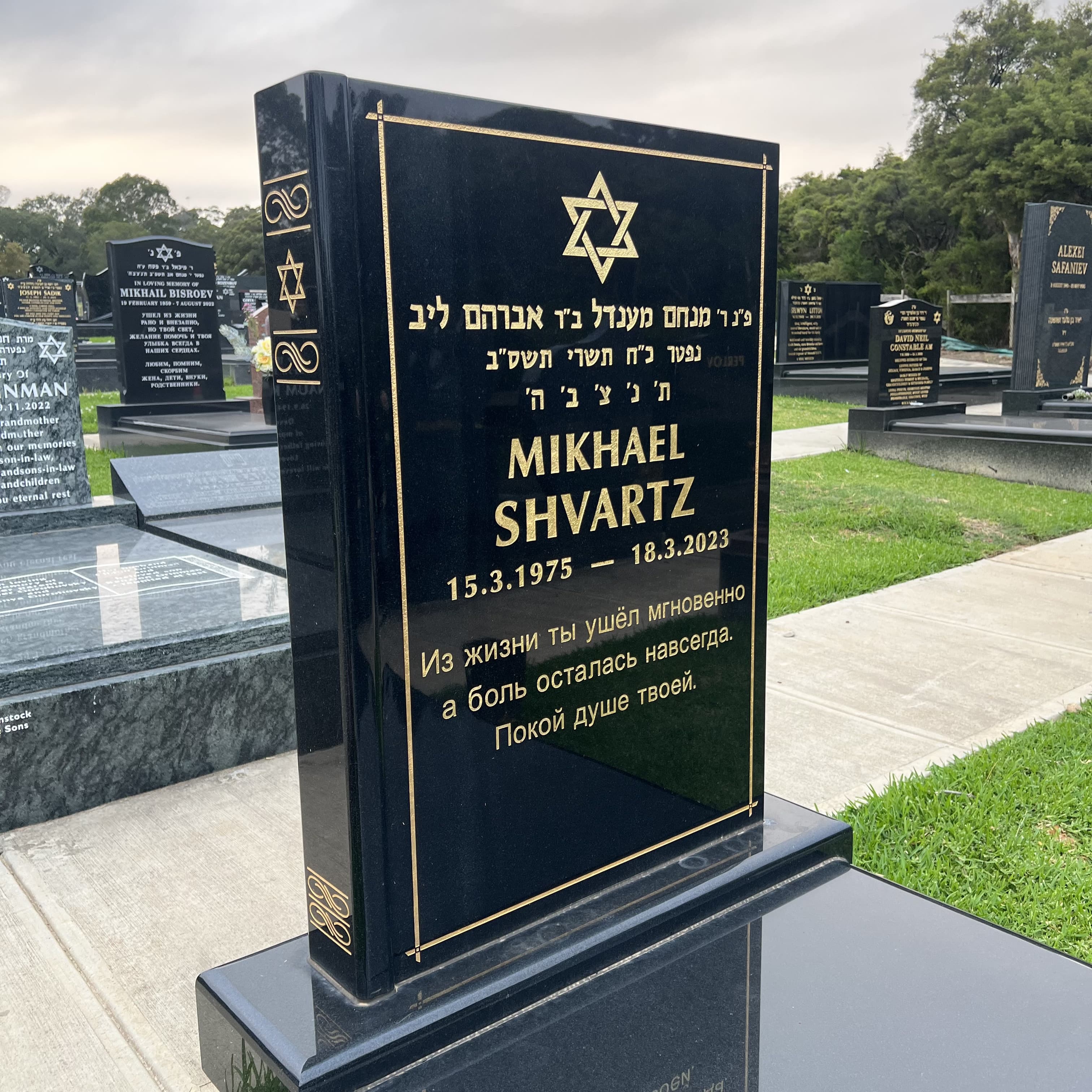 Single book shaped headstone with jet black granite and gold lettering.