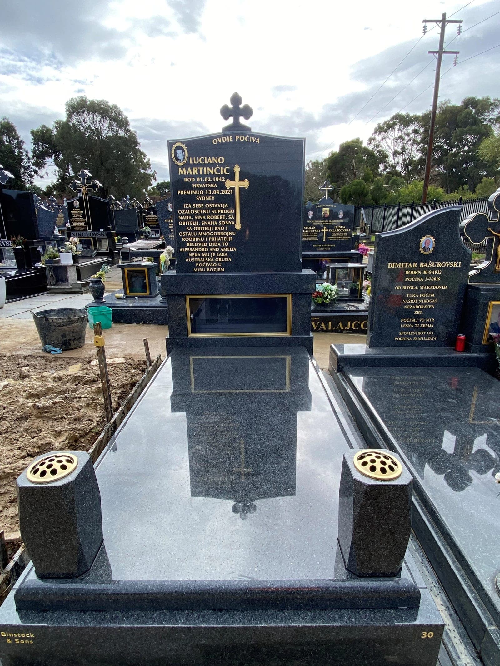 Double full Macedonian gravestone with a serpentine-shaped (with cross) headstone, gold leaf lettering, and jet black granite.