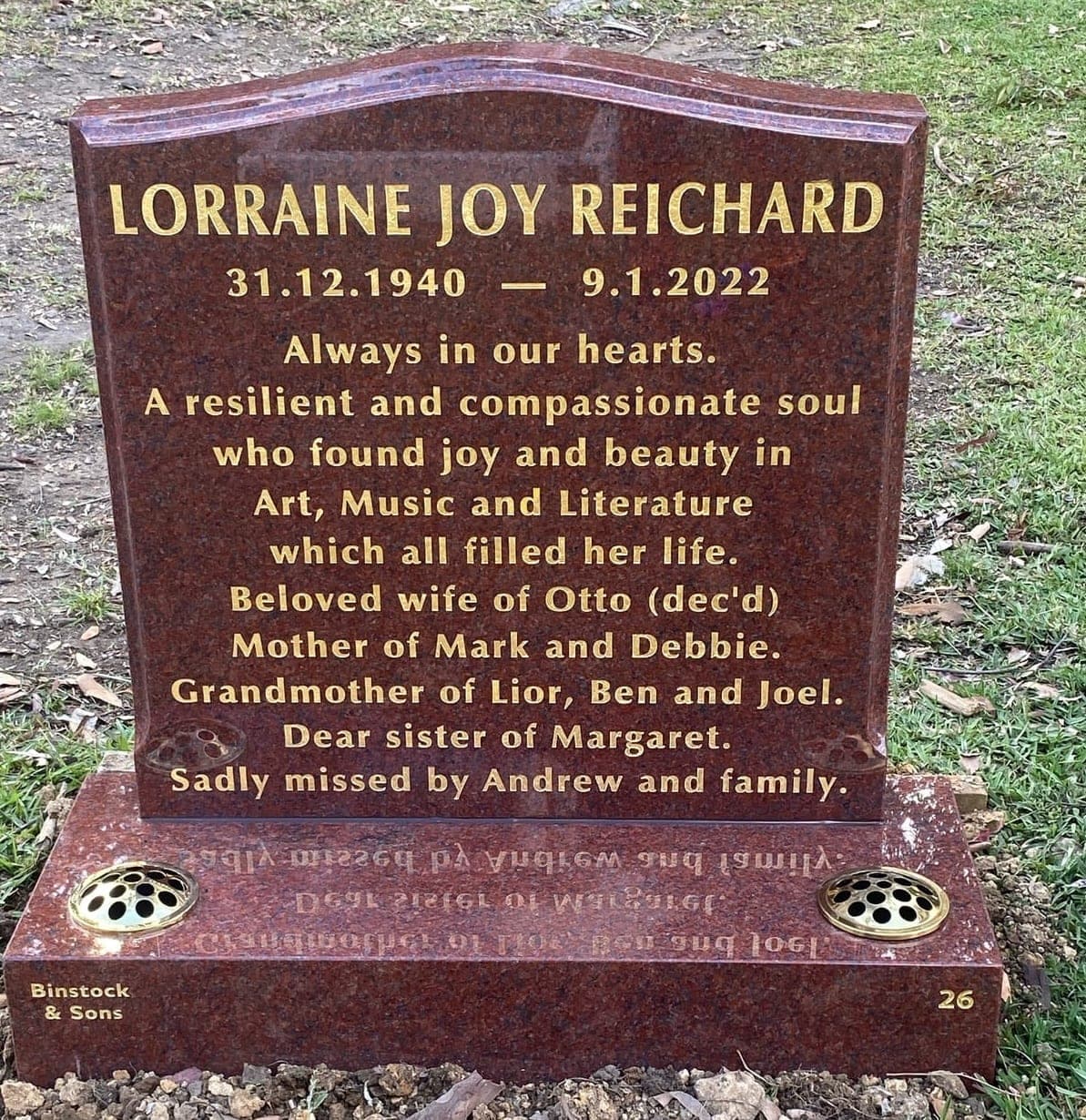 Single memorial with a serpentine-shaped headstone, base, gold leaf lettering, and ruby red granite.
