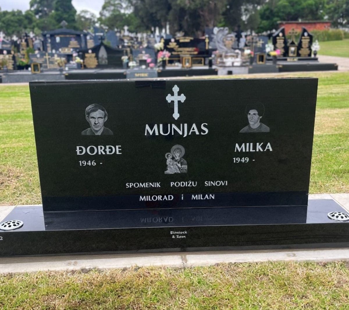 Double monument with a serpentine-shaped headstone, base, cut-in lettering, and jet black granite.