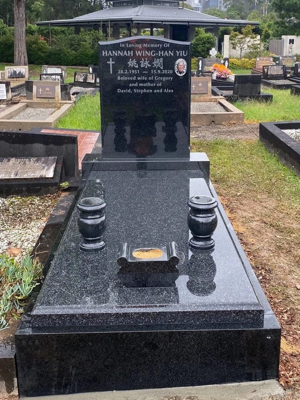 Single full gravestone with a serpentine-shaped headstone, natural cut-in lettering, with galaxy black granite (headstone) and noble grey granite (slab).
