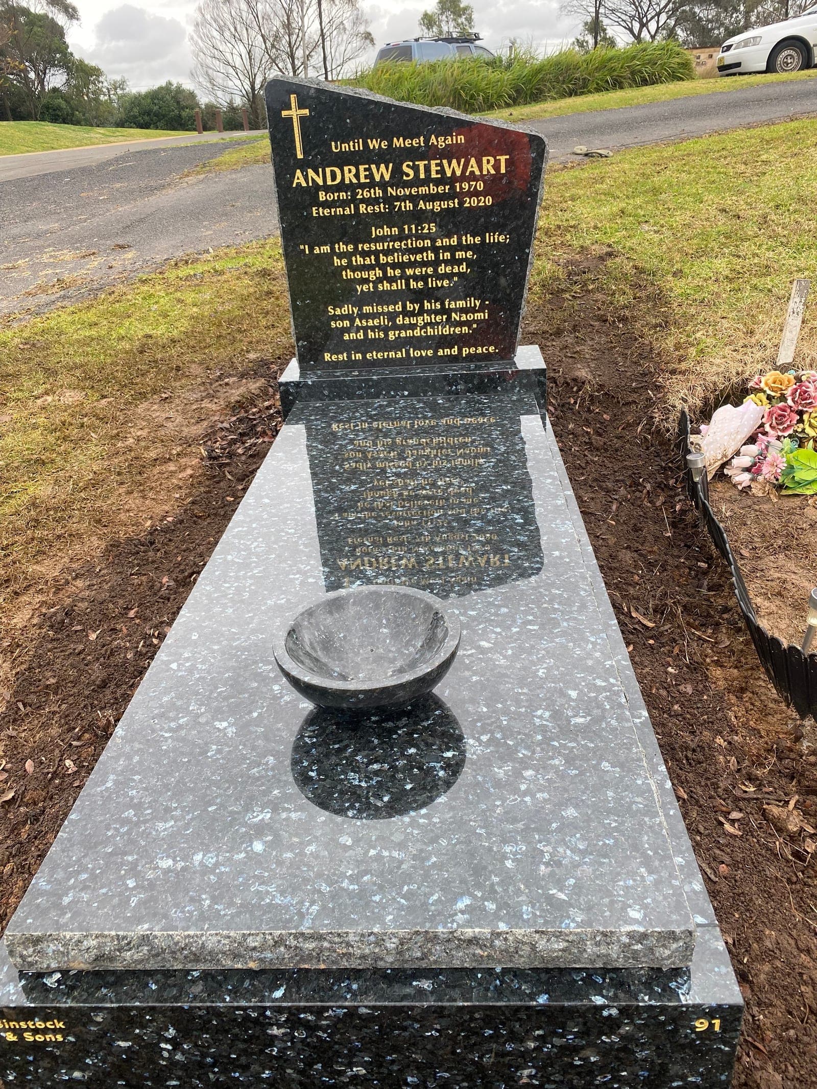 Single full Anglican gravestone with a sloping top shaped headstone, gold leaf lettering, and emerald pearl granite.